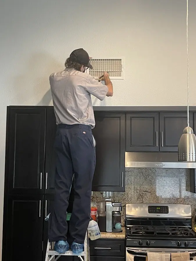 Technician inspecting an air vent during HVAC service in Denair